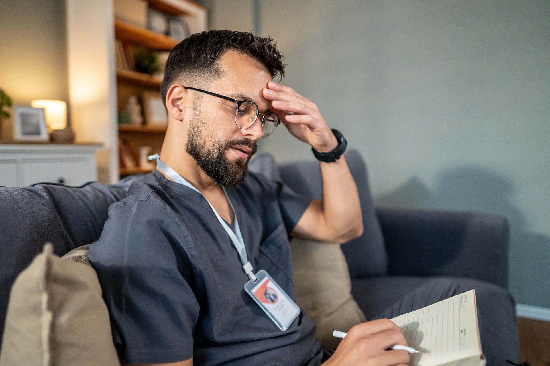 Stressed male healthcare worker writing notes at home